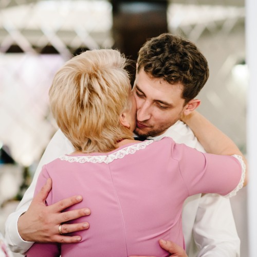 A groom and his mother enjoying a nice moment. They're hugging one another as he gets ready to walk down the aisle.