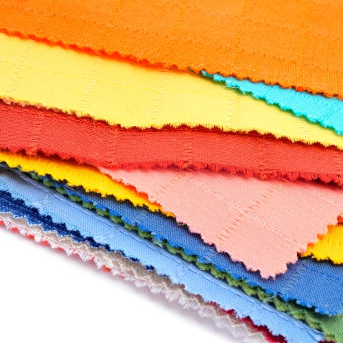 A close-up of the very edges of a stack of colorful fabric pieces on top of a white background.