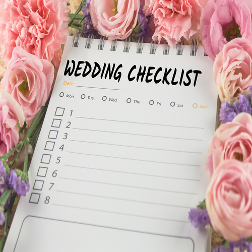 A wedding checklist with several empty bullet points. The checklist is surrounded by pink roses and purple flowers.