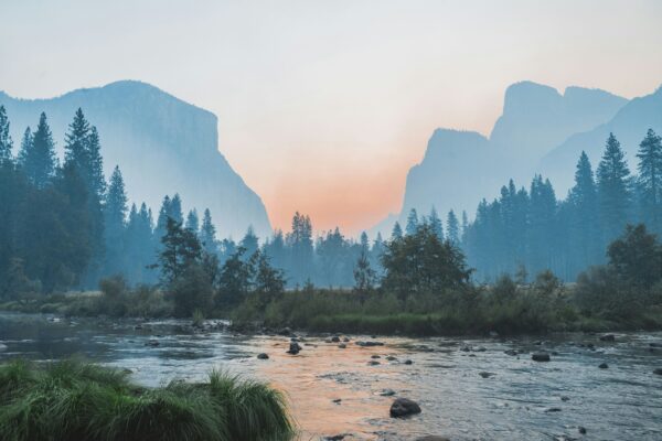 Scenic sunrise in Yosemite Valley with river, misty mountains, pine trees, and granite cliffs