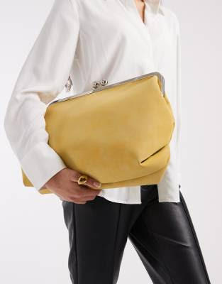 Buttermilk yellow oversized clutch bag styled with white blouse and black leather pants