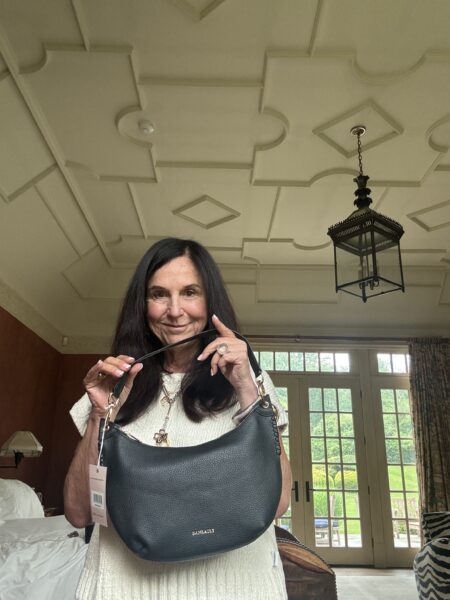 Stacy Geisinger holds a black Daneault handbag while smiling in her Bedford, New York home.