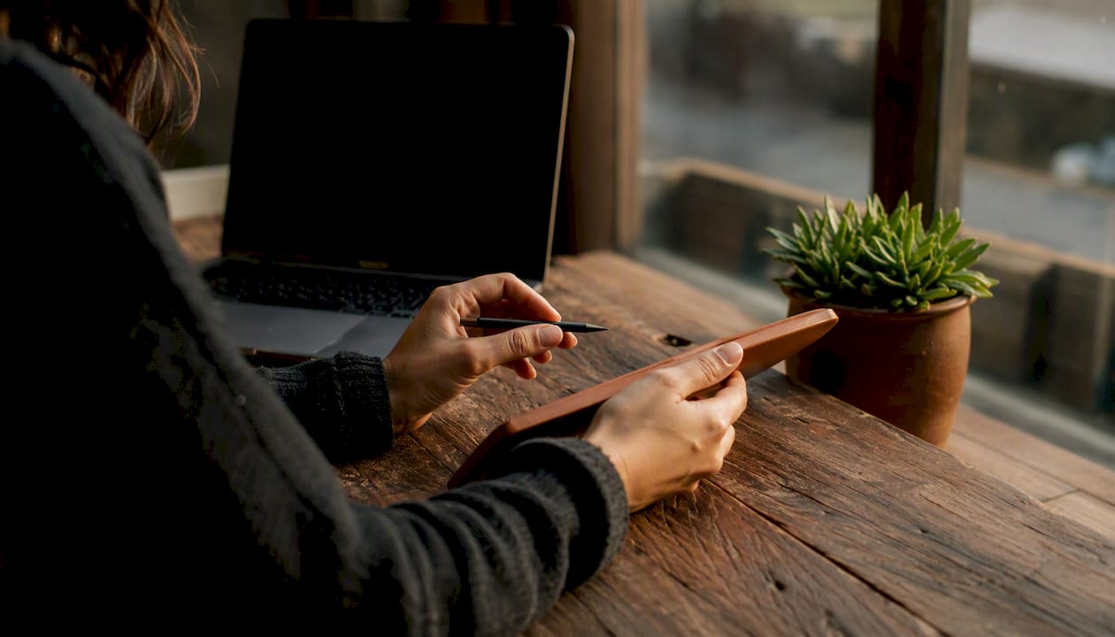 Hands holding smartphone near rustic notebook