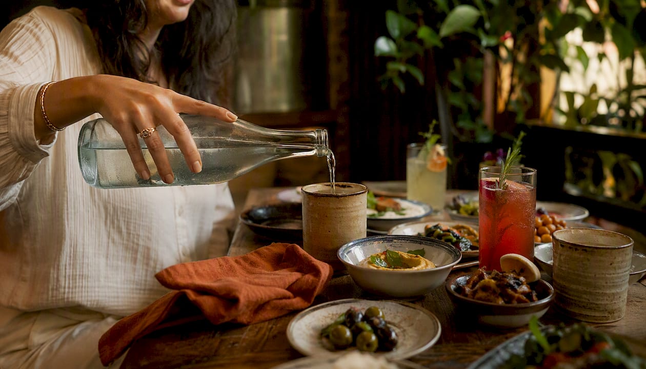 Hands pouring water at semi-private group dinner