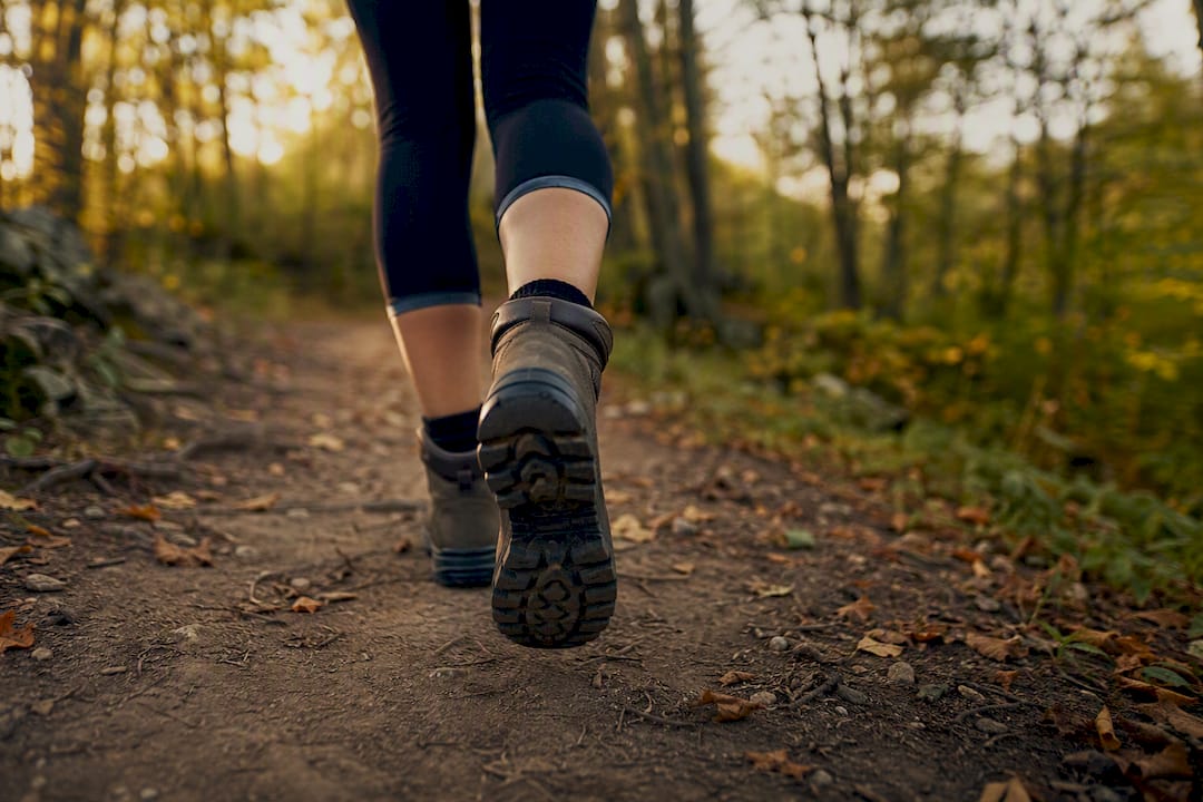 Feet walking briskly on forest trail