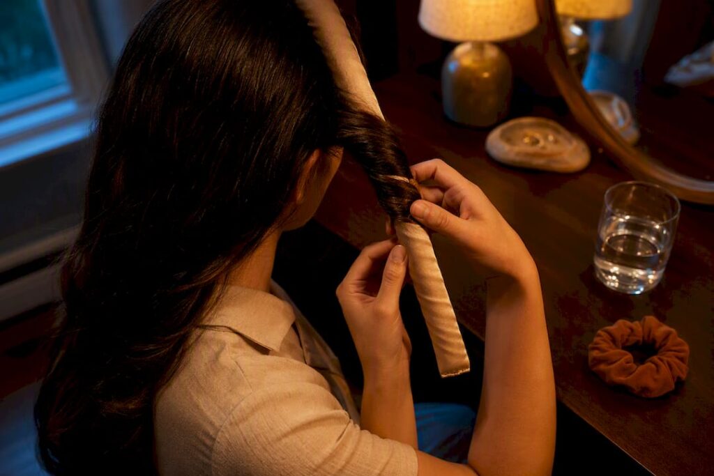 Hands wrapping damp hair around satin rod