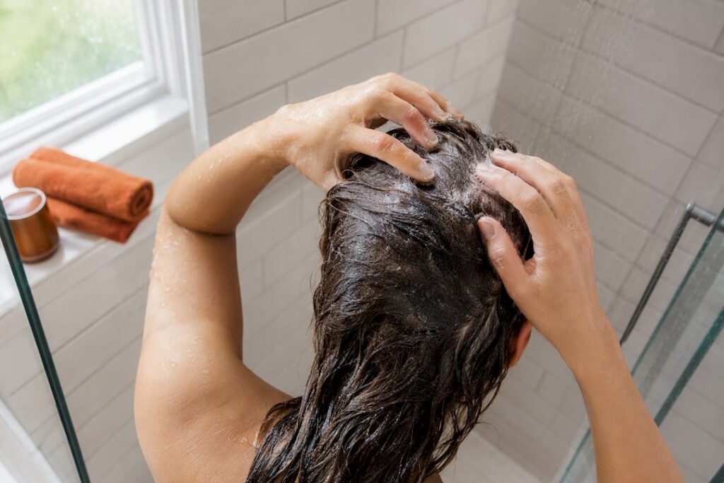 Hands massaging shampoo into wet scalp