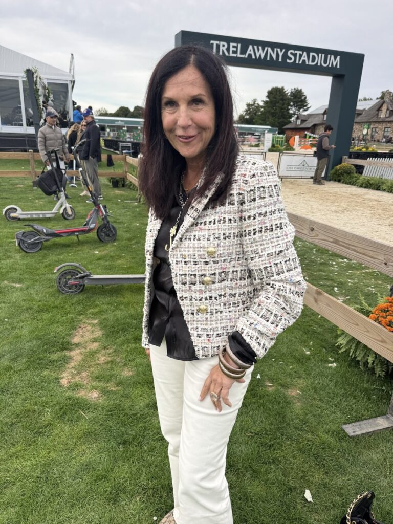 Stacy outdoors in a tweed jacket and white pants
