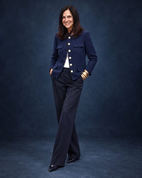 AI try-on visualization of Stacy in a navy tweed jacket against a dark blue studio background