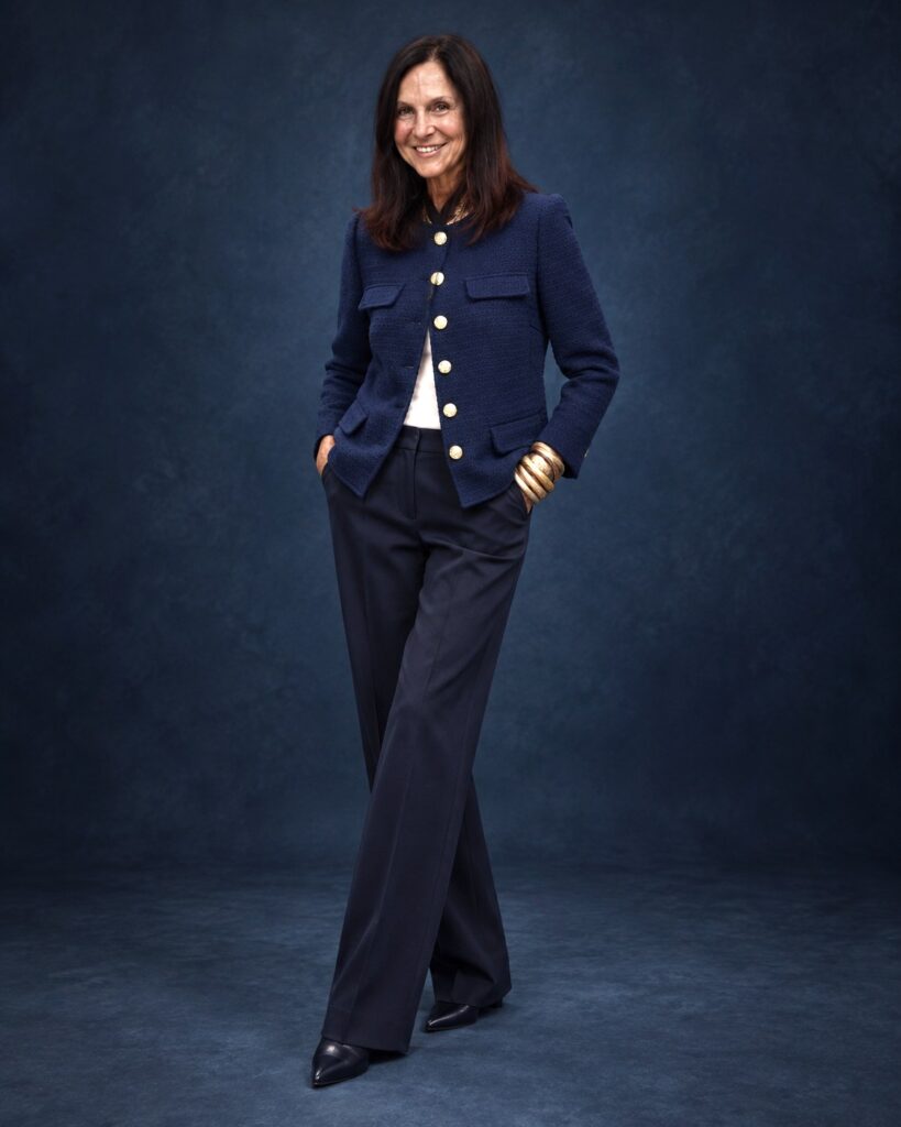 AI try-on visualization of Stacy in a navy tweed jacket against a dark blue studio background